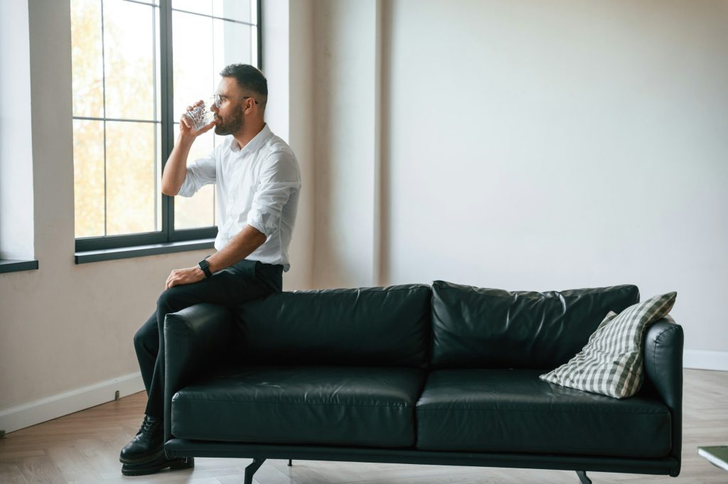 Elegant man in business clothes is indoors with glass of water